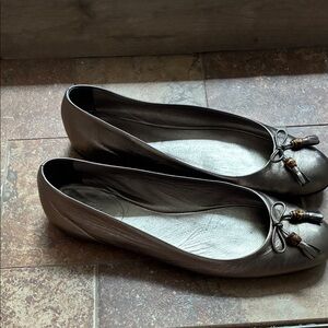 Gucci Metallic Bronze Flats with Tassels. Small discoloration on left back heel.